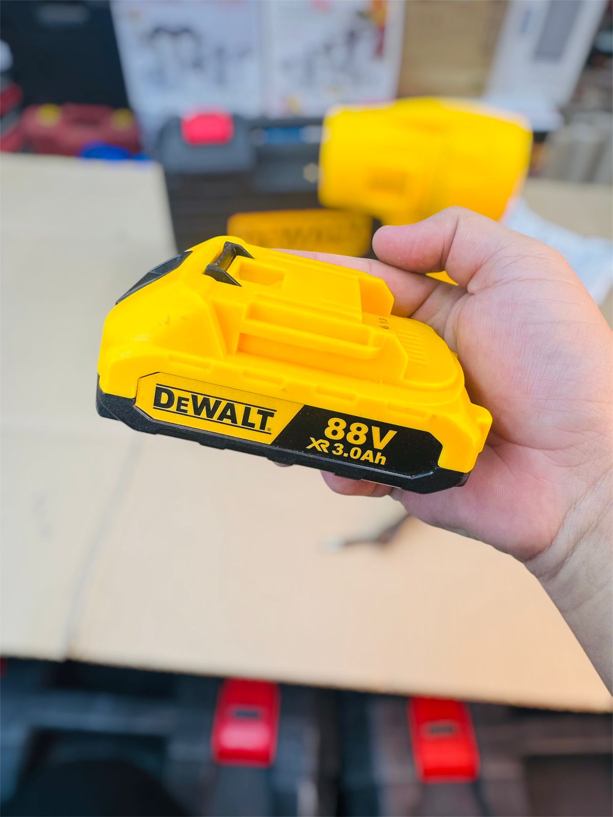 Hand holding a Dewalt 88V battery pack with a blurred background